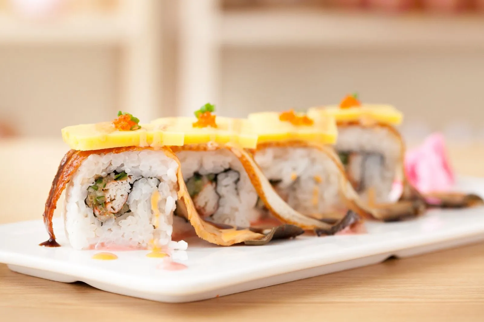 Grilled eel sushi rolls topped with mango and fish roe
